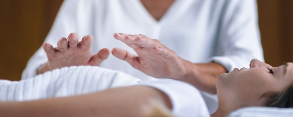 Energy healing session with a practitioner performing hands-on or hands-off healing over a relaxed patient, promoting balance and well-being., benefits of energy healing